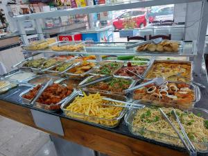 a buffet filled with different types of food in trays at Hotel Joia Fina in Aparecida +27 photos