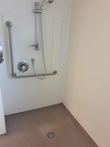 een kleine kamer met een douche en een afvoer bij At Eden Park Motel in Auckland