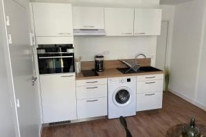 een keuken met witte kasten en een wasmachine bij Le Poulorio 5 - Proche Gare By Locly in Lorient