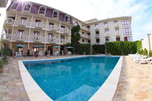 a hotel with a swimming pool in front of a building at Villa Fellini in Sudak