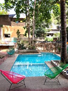 a swimming pool with two chairs and a table at Hostal Tortuga in Sayulita