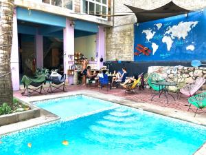 una piscina con sillas y gente sentada alrededor de una mesa en Hostal Tortuga en Sayulita