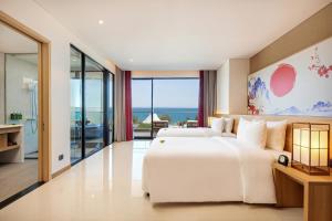 Da Nang - Mikazuki Japanese Resorts & Spa في دا نانغ: غرفة نوم مع سرير أبيض كبير وإطلالة على المحيط
