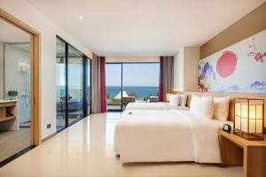 ダナンにあるDa Nang - Mikazuki Japanese Resorts & Spaの海の景色を望むベッドルーム1室(大きな白いベッド1台付)