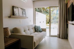 ein Wohnzimmer mit einem Sofa und einer Glasschiebetür in der Unterkunft Qavi - Flat completo com piscina privativa #ÎledePipa in Pipa