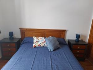 カレタ・デ・ファマラにあるCasa la Caletaのベッド1台(青い掛け布団、ナイトスタンド2台付)