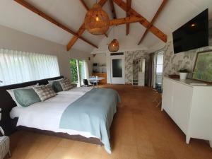 a bedroom with a large bed and a living room at B&B De Boerderij in Haren