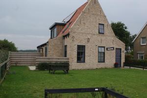 an old brick building with a bench in front of it at Antares-Ameland in Hollum