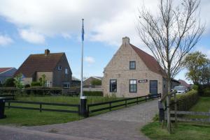 an old stone building with a fence in front of it at Antares-Ameland in Hollum