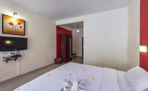 1 dormitorio con 1 cama blanca y TV de pantalla plana en Deshadan Mountain Resort -The highest resort in Munnar, en Munnar
