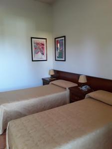 een hotelkamer met twee bedden en twee foto's aan de muur bij Albergo Al Portico in Azzano Decimo