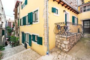 a yellow building with green shutters and a balcony at Yellow House Rovinj in Rovinj
