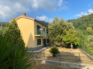 Casa amarilla con balcón y árboles en Appartamenti Borgo San Pietro, en Deiva Marina