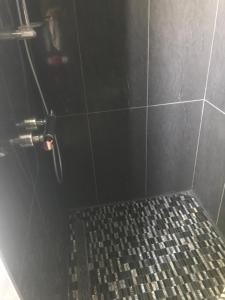 La salle de bains est pourvue d'une douche et de carrelage noir. dans l'établissement Résidence du bord de loire, à Decize