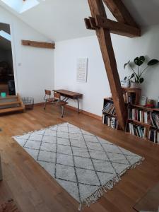 Zimmer mit einem Tisch und einem Teppich auf einem Holzboden in der Unterkunft Les écuries du château des Rieux in Saint-Martin-Terressus