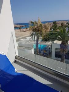 a balcony with a view of a beach and palm trees at Christopher's Sandy Beach Suites in Ayia Napa