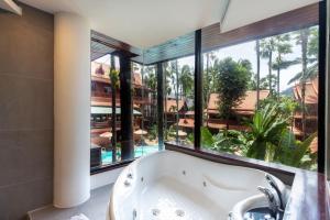 a bath tub in a bathroom with a large window at Royal Phawadee Village Patong - SHA Plus in Patong Beach