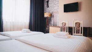two beds in a hotel room with a tv on the wall at Wine Hotel Cesarica in Međugorje