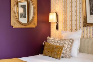 Schlafzimmer mit lila Wänden und einem Bett mit Kissen in der Unterkunft Hôtel Le Saint Christophe in La Baule