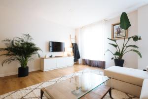 a living room with a couch and two potted plants at Pz triana amplio, moderno y luminoso apt 2d 2b in Seville