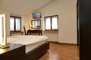 a bedroom with a bed and a table and windows at Apartments Colombara Bardolino in Bardolino