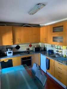 a kitchen with wooden cabinets and a glass table at Vissaium Rooms- checkin até as 20h in Viseu
