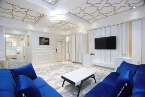 a living room with a blue couch and a tv at Reikartz Amirun Tashkent in Tashkent