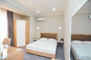 a hotel room with two beds and a desk at Reikartz Amirun Tashkent in Tashkent