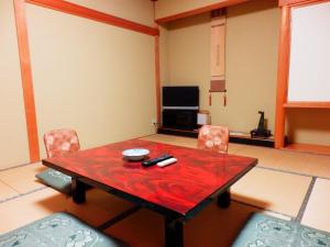 sala de estar con mesa, sillas y TV en Nakayasu Ryokan, en Kanazawa