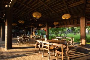 a restaurant with wooden tables and chairs on a deck at The Kirana Tembok in Tejakula