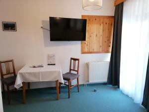Habitación con mesa, sillas y TV en la pared. en Haus Oswald am See, en Hermagor
