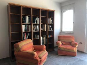 a living room with two chairs and a book shelf at Verde Matematico in Vico del Gargano