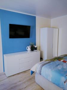 1 dormitorio con vestidor blanco y TV en una pared azul en Gästehaus Anglerklause, en Allstedt