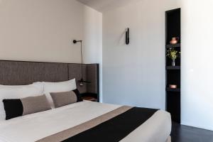 a bedroom with a large bed with white sheets and pillows at Nimbus Santorini in Oia