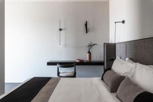 a bedroom with a bed and a desk with a chair at Nimbus Santorini in Oia