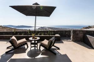 a patio with a table and chairs and an umbrella at Nimbus Santorini in Oia