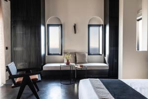 a bedroom with a bed and two windows at Nimbus Santorini in Oia