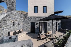 a stone building with a couch and an umbrella at Nimbus Santorini in Oia
