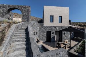 a house with a stone wall and stairs at Nimbus Santorini in Oia