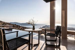 a table and chairs on a balcony with a view of the ocean at Nimbus Santorini in Oia