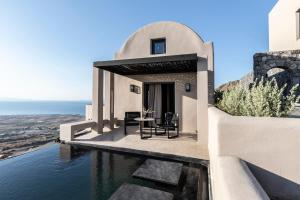 a villa with a swimming pool and a house at Nimbus Santorini in Oia