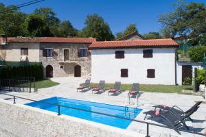 a pool in a yard with chairs and a house at Casa Storia & Casa Antica in Veprinac