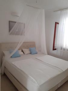 a white bedroom with two beds and a window at Apartment Zečevo in Zečevo