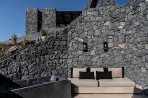 a couch sitting in front of a stone wall at Nimbus Santorini in Oia