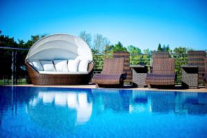 a swimming pool with a gazebo and chairs next to a swimming pool at Tristan Hotel & SPA in Kąty Rybackie