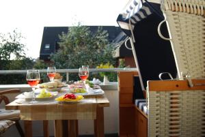 a table with food and wine glasses on a balcony at Luxuswohnung Abendsonne in Wenningstedt