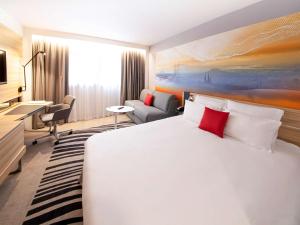 a hotel room with a large bed and a desk at Novotel Clermont-Ferrand in Clermont-Ferrand