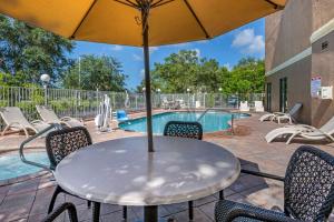 a table with chairs and an umbrella next to a pool at Comfort Suites Fort Pierce I-95 in Fort Pierce