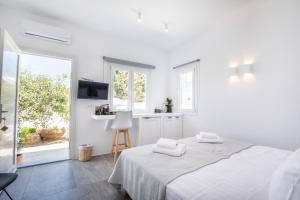 a white bedroom with two beds and a window at Mytheo in Mikonos