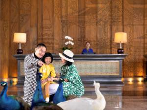 a man and a woman and a child sitting next to a goose at Pullman Resort Xishuangbanna in Jinghong